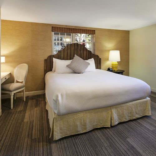 A cozy hotel bedroom with a large bed, neutral tones, nightstands, lamps, a window, and a soft, inviting atmosphere.