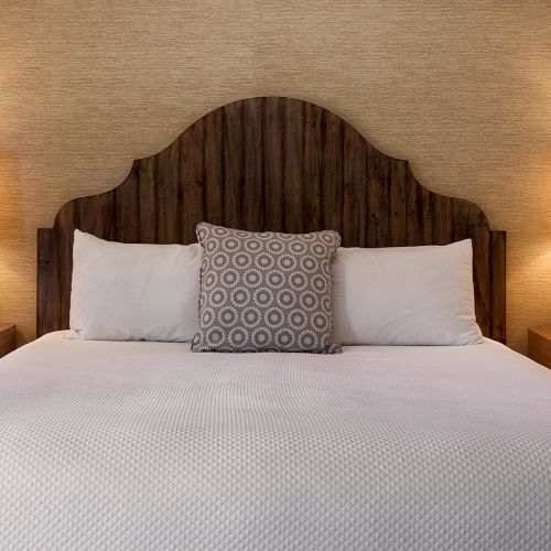 A cozy bedroom with a bed, two lamps on bedside tables, and a plush headboard; crisp white bedding and warm ambient lighting.