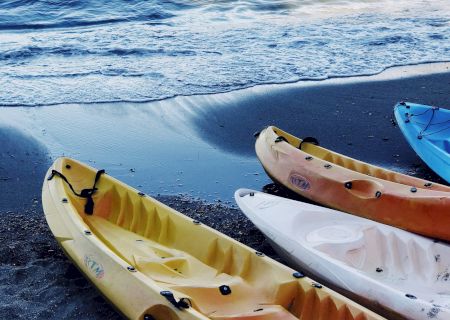 Small wooden boats on calm blue water, with a rocky shore in the background. Ends with a period.